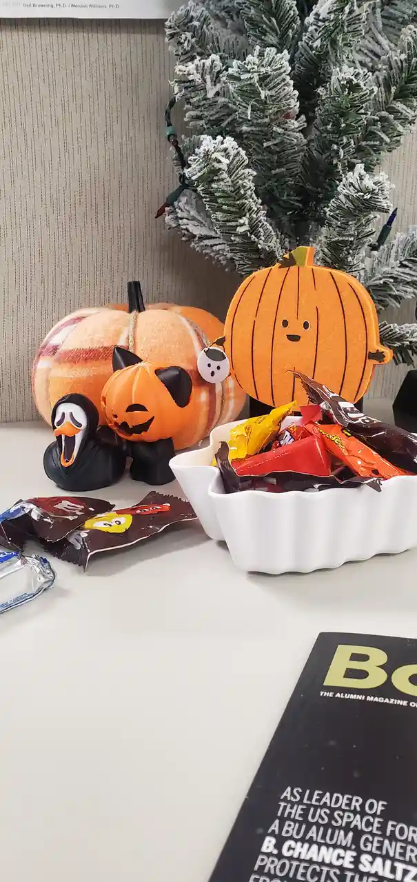 A desk setup features Halloween decorations including a plush pumpkin, a jack-o'-lantern figurine, and a screaming ghost…