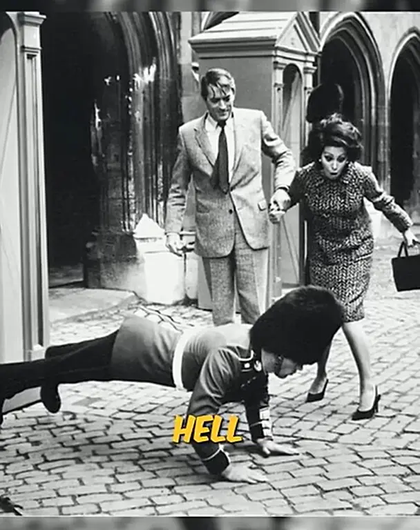 A black and white photo shows a man in a British military uniform doing a push-up on a cobblestone street. Behind him, a man…