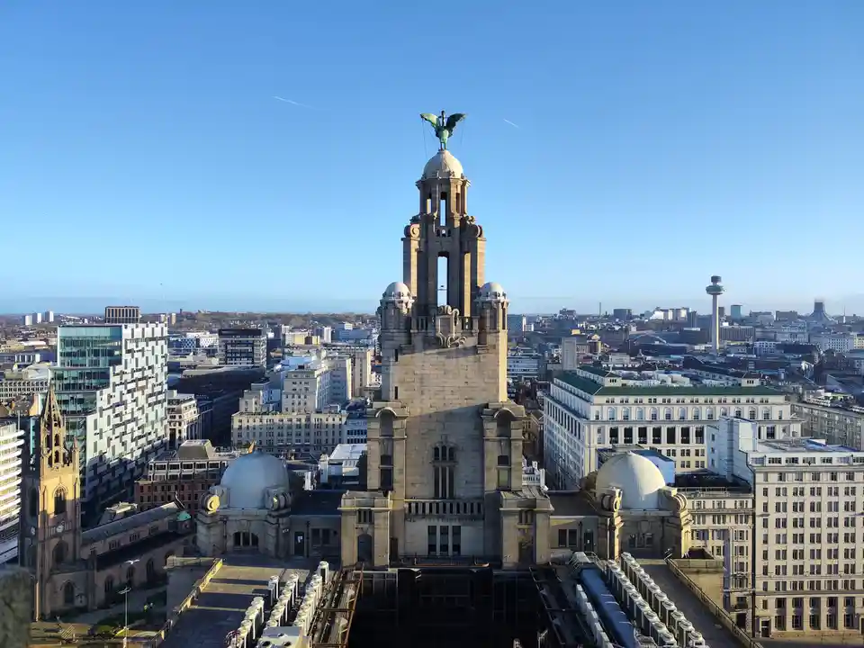 A clear, sunny day photo of the iconic Liver Building in Liverpool, UK, with its famous Liver Birds atop the towers…