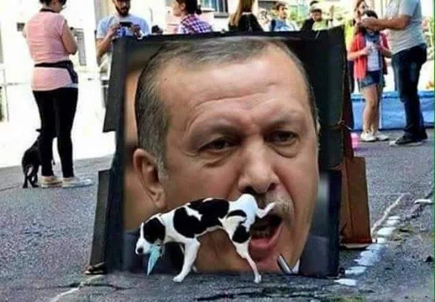 A large cutout of Turkish President Recep Tayyip Erdoğan's face is held upright on a street, with a small black-and-white…