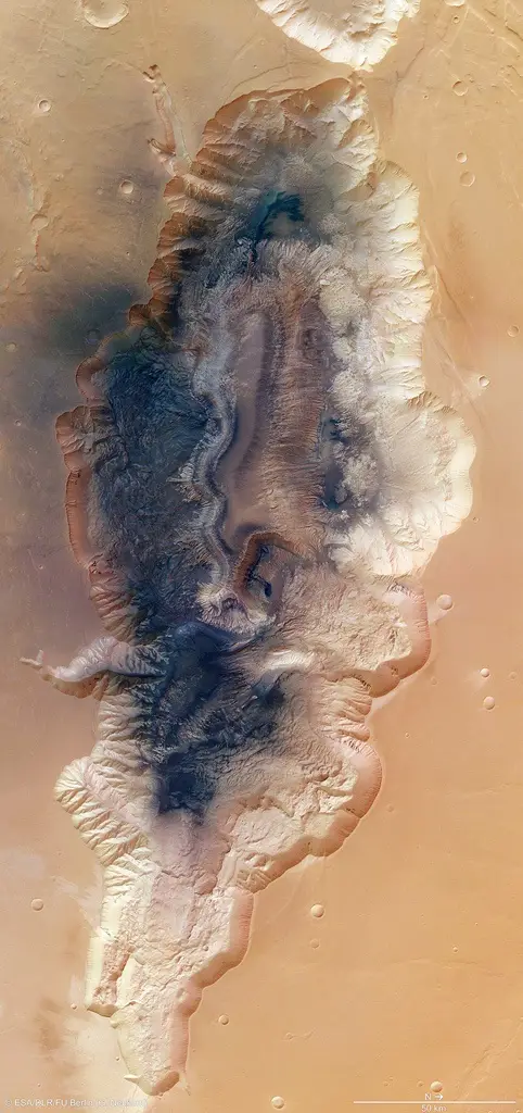 a satellite image of a Martian valley with layered rock formations and a dark central channel, overlaid with the text 'this…