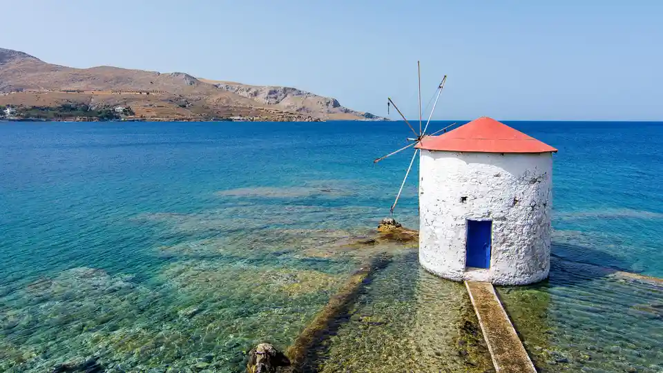Situated on a European island near Asia, this picturesque windmill stands on the water's edge. Located on Leros, a Greek…