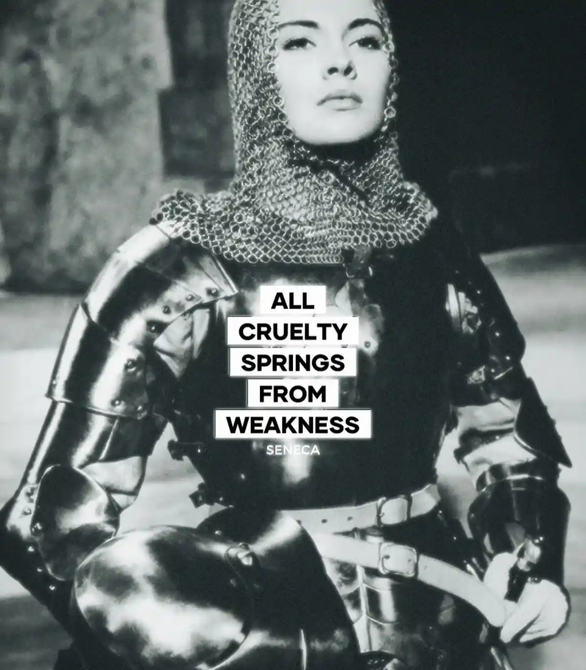 A black-and-white photo shows a woman in full medieval armor, including a chainmail coif and metal breastplate, looking…