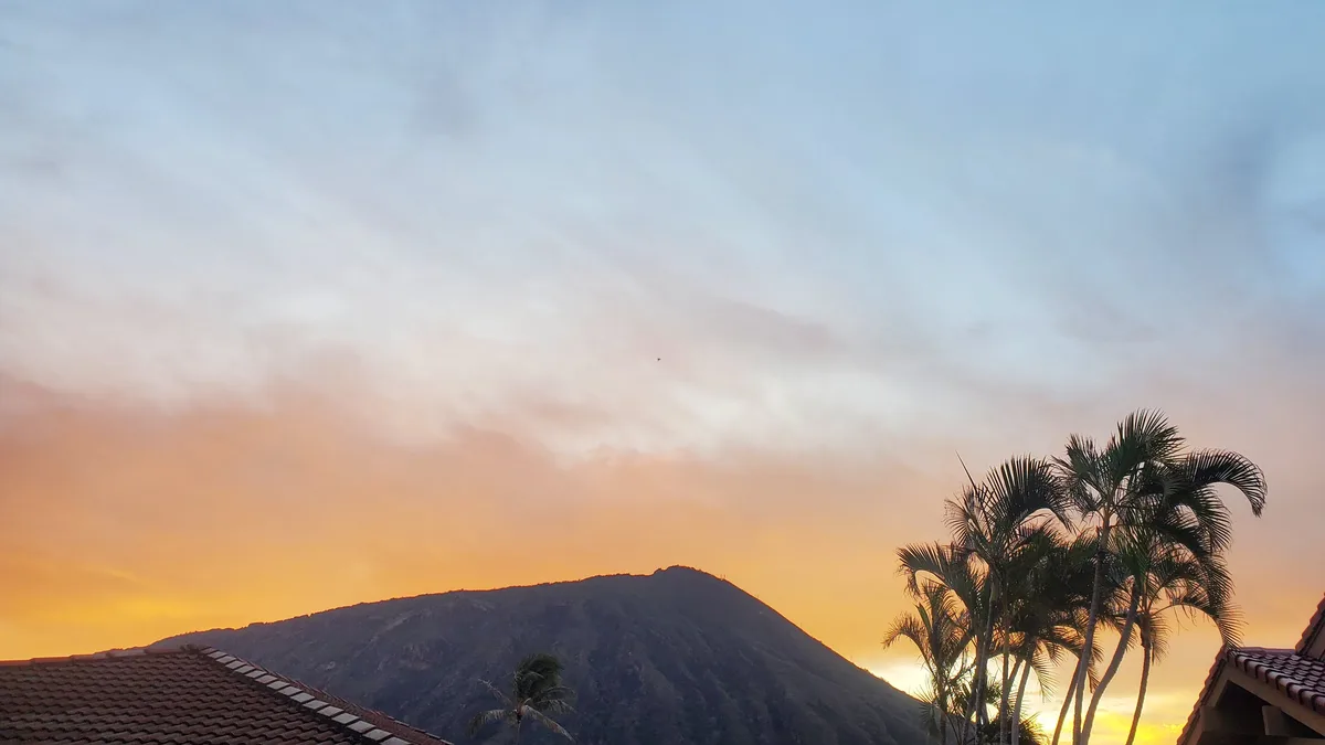 A scenic photo of a mountain at sunset with palm trees and tiled rooftops, overlaid with the text 'i'm not lazy, i'm in…