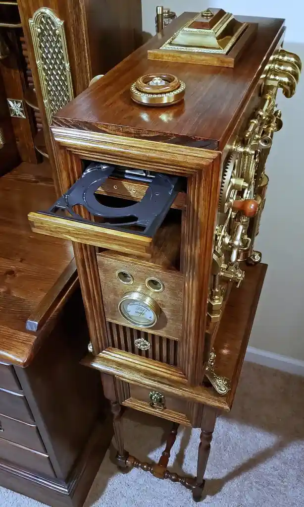 A highly ornate wooden cabinet with brass gears, dials, and decorative elements resembling steampunk design, but its open…
