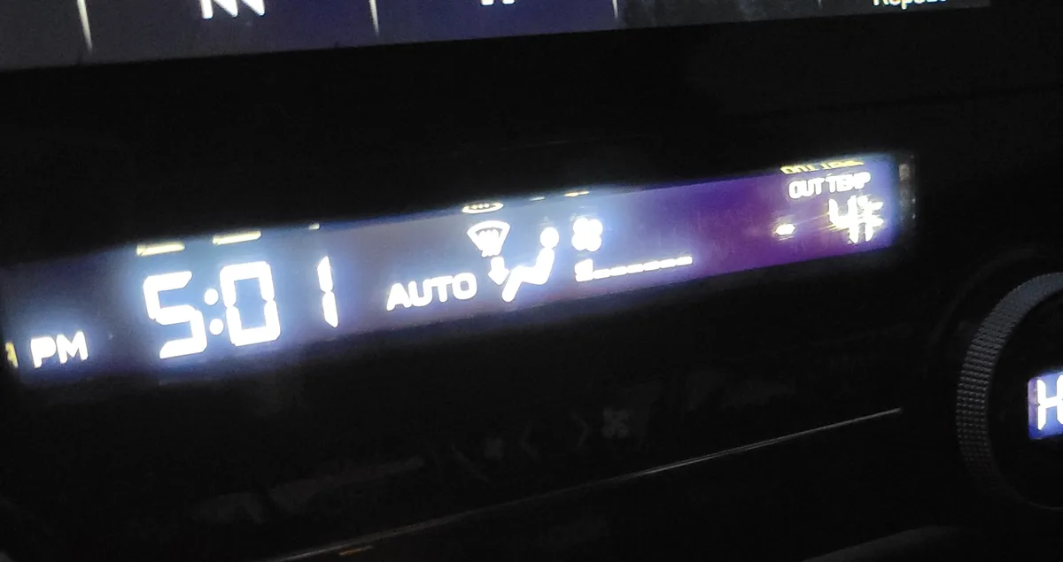 A close-up of a car's digital dashboard display showing the time as 5:01 PM, with 'AUTO' climate control and an outside…