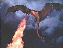 A large, dark-colored dragon with spread wings is shown flying against a stormy, cloudy sky, exhaling a powerful stream of…
