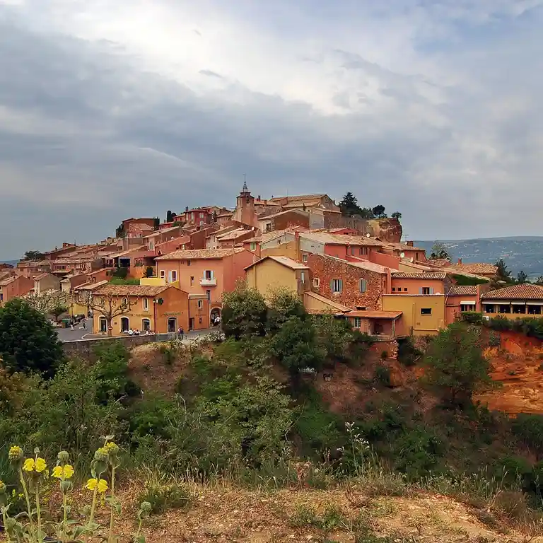 A scenic photo of a hillside village with terracotta-roofed buildings under a cloudy sky, overlaid with the text 'i'm not…