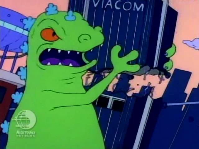 A green, angry cartoon monster with sharp teeth and orange eyes stands in front of a building labeled 'VIACOM', gesturing…