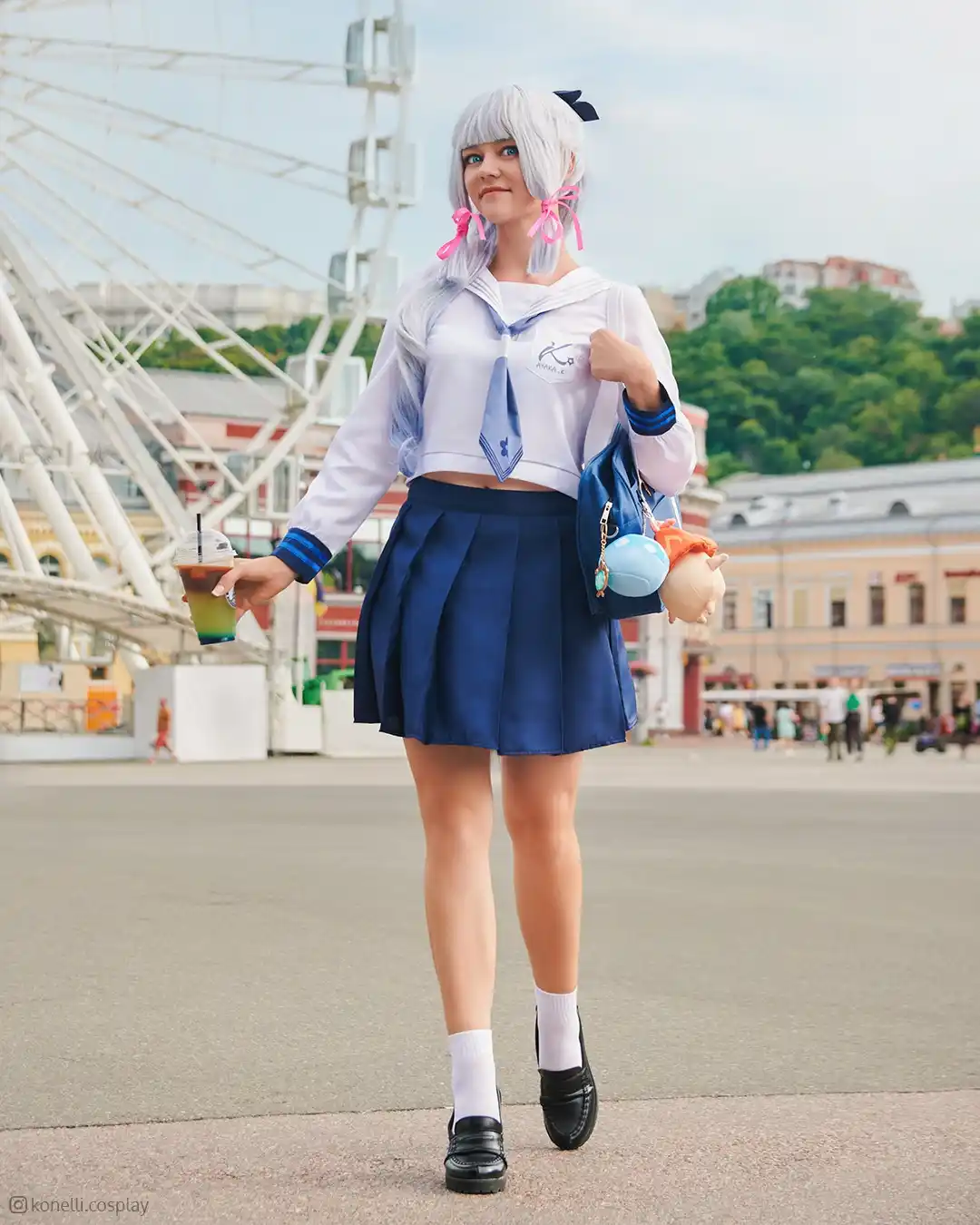 A person in a detailed anime-style sailor uniform cosplay, featuring a white cropped top, blue pleated skirt, and black…