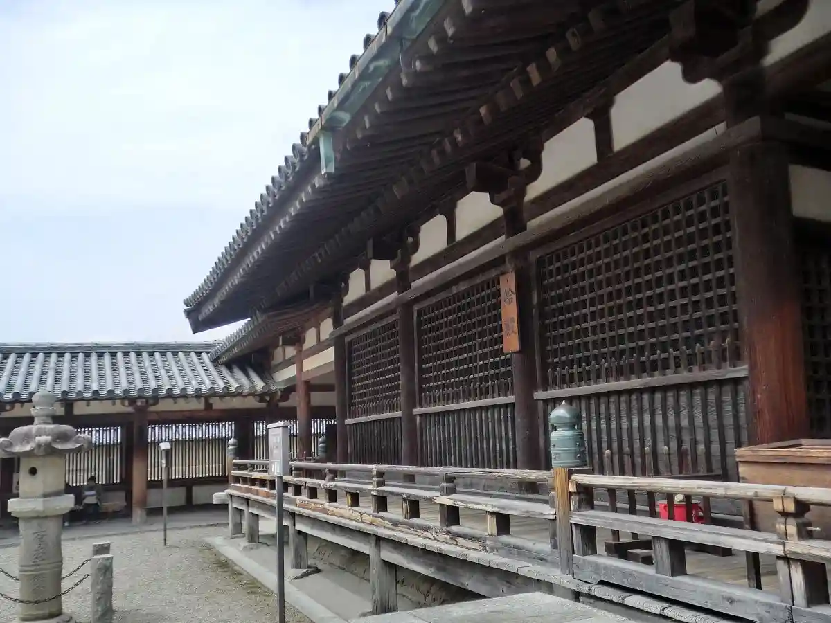 a photograph of a traditional japanese wooden temple building with a tiled roof, wooden railings, and stone lanterns…