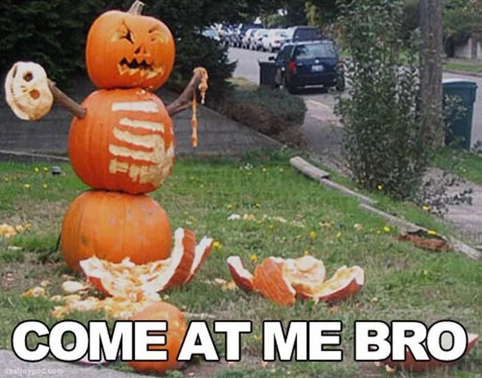 A three-pumpkin Halloween decoration stands in a grassy yard, with the top pumpkin carved as a face, the middle one showing…