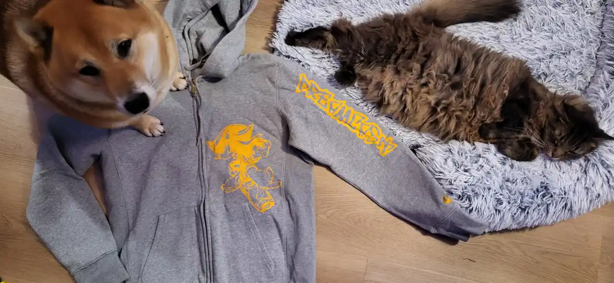 A shiba inu dog looks down at a grey zip-up hoodie with a yellow Sonic the Hedgehog graphic and 'DREAMS' text on the sleeve…