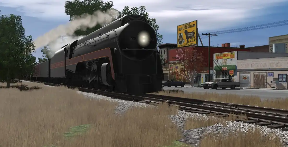 A large black steam locomotive, numbered 611, emits smoke as it travels on tracks through a grassy field beside a small town…