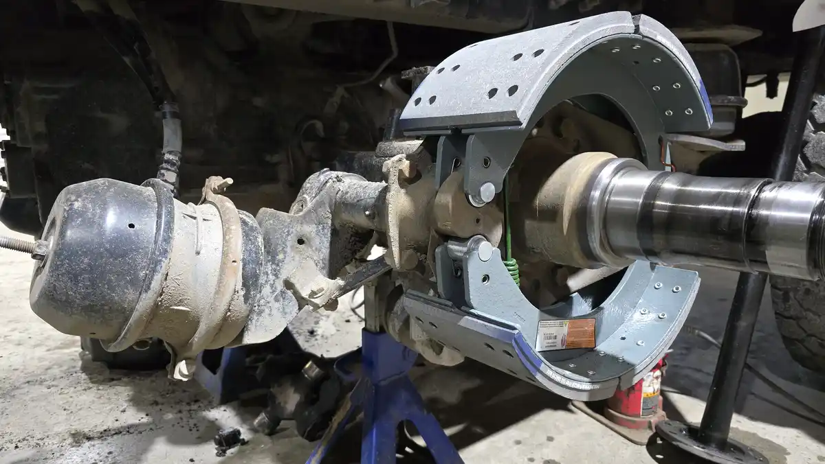A close-up photo shows a vehicle's differential assembly, with its housing partially disassembled and resting on a blue jack…