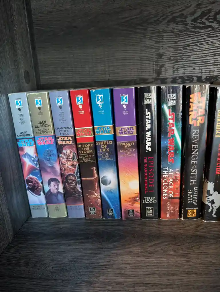 A row of Star Wars paperback books from the Expanded Universe, including titles like 'Dark Apprentice', 'Jedi Search'…