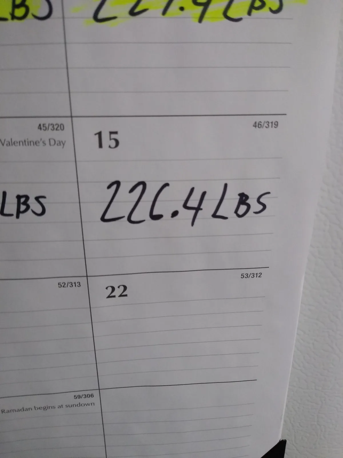 A close-up of a handwritten weight log in a notebook, showing a weight of 226.4 lbs on February 15th, with Valentine's Day…