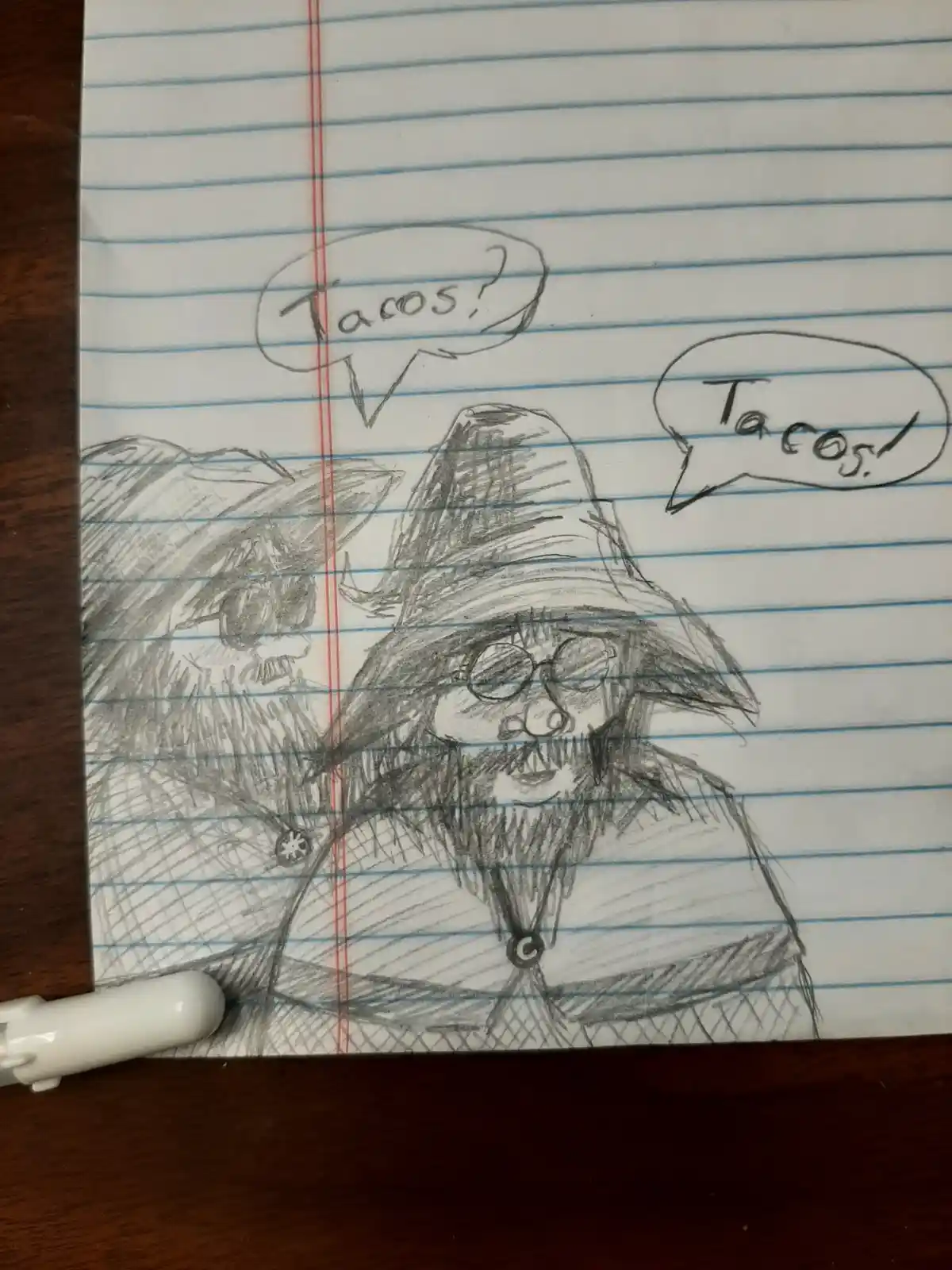 A hand-drawn pencil sketch on blue-lined notebook paper shows two cartoonish, bearded, mustachioed men in wide-brimmed hats…