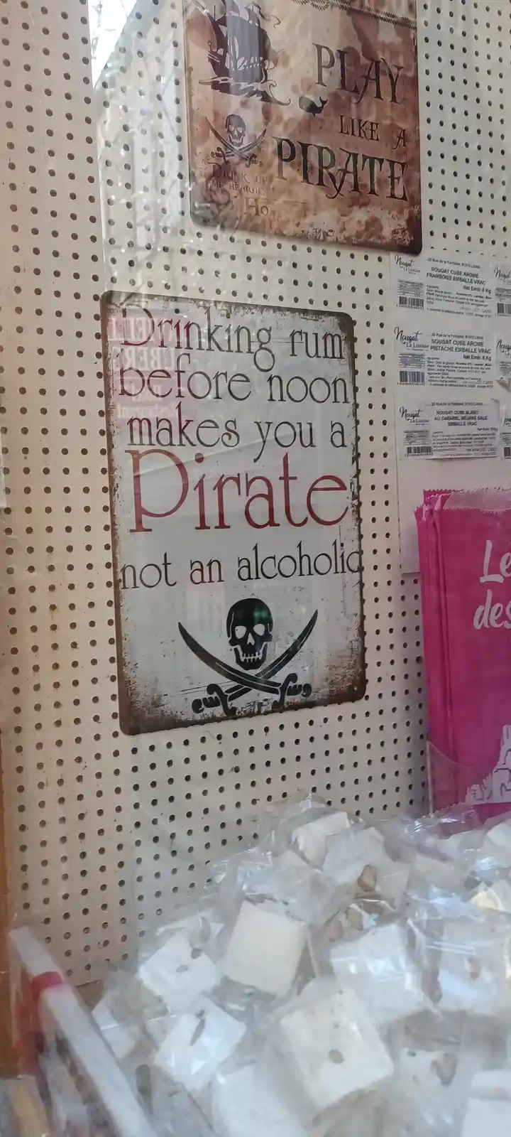 A rustic metal sign with a skull and crossbones reads 'Drinking rum before noon makes you a Pirate not an alcoholic,'…