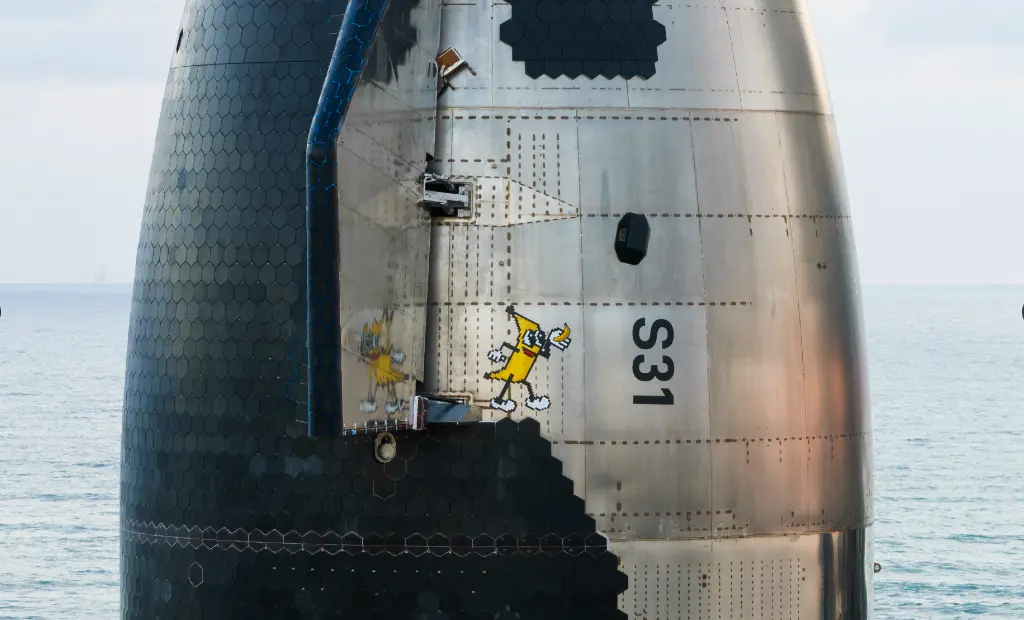 A close-up photo of a SpaceX rocket booster, marked with the identifier S31, shows two cartoon characters, resembling…