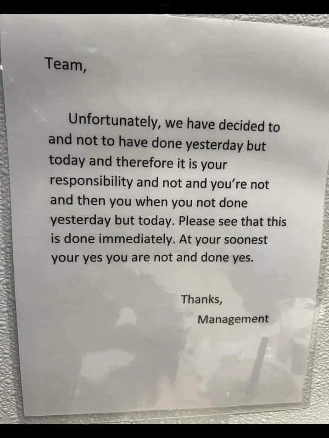 A blurry photo of a printed note addressed to 'Team' from 'Management' with a grammatically incorrect message about…