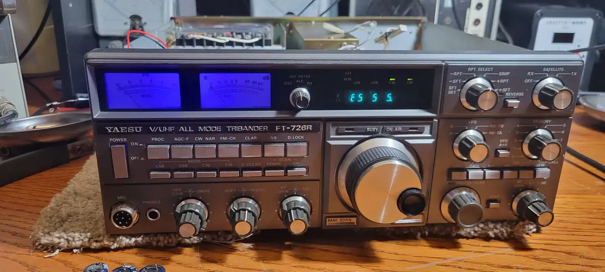 A Yaesu FT-726R V/UHF all-mode radio sits on a wooden desk, its digital display showing '5 5 5 5' in green numerals…