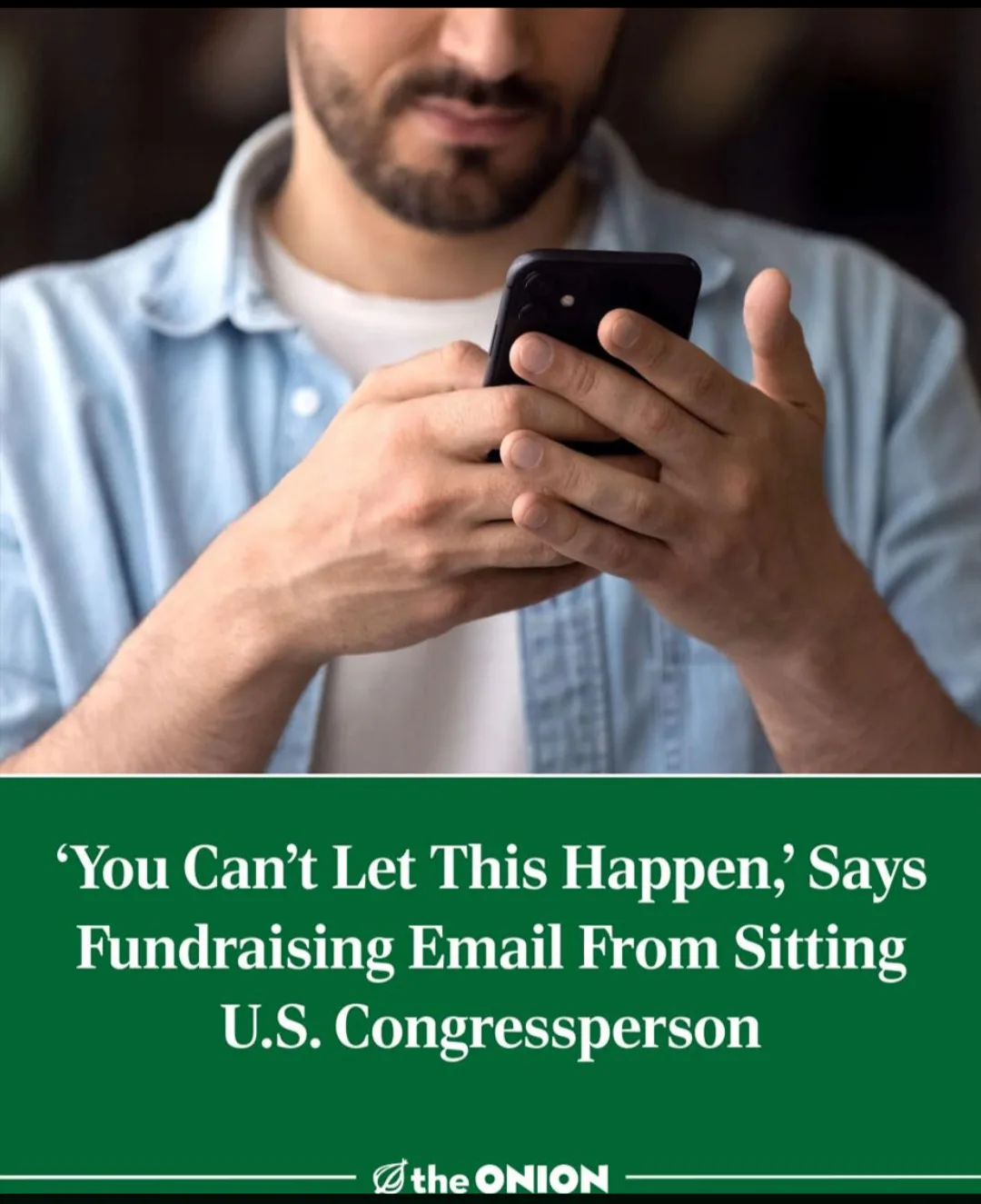 A man with a beard wearing a light blue shirt is looking down at a black smartphone held in both hands. Below the image, a…