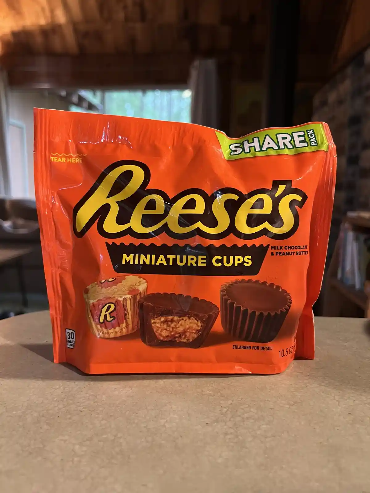 A bright orange bag of Reese's Miniature Cups sits on a countertop, featuring images of the chocolate peanut butter cups and…