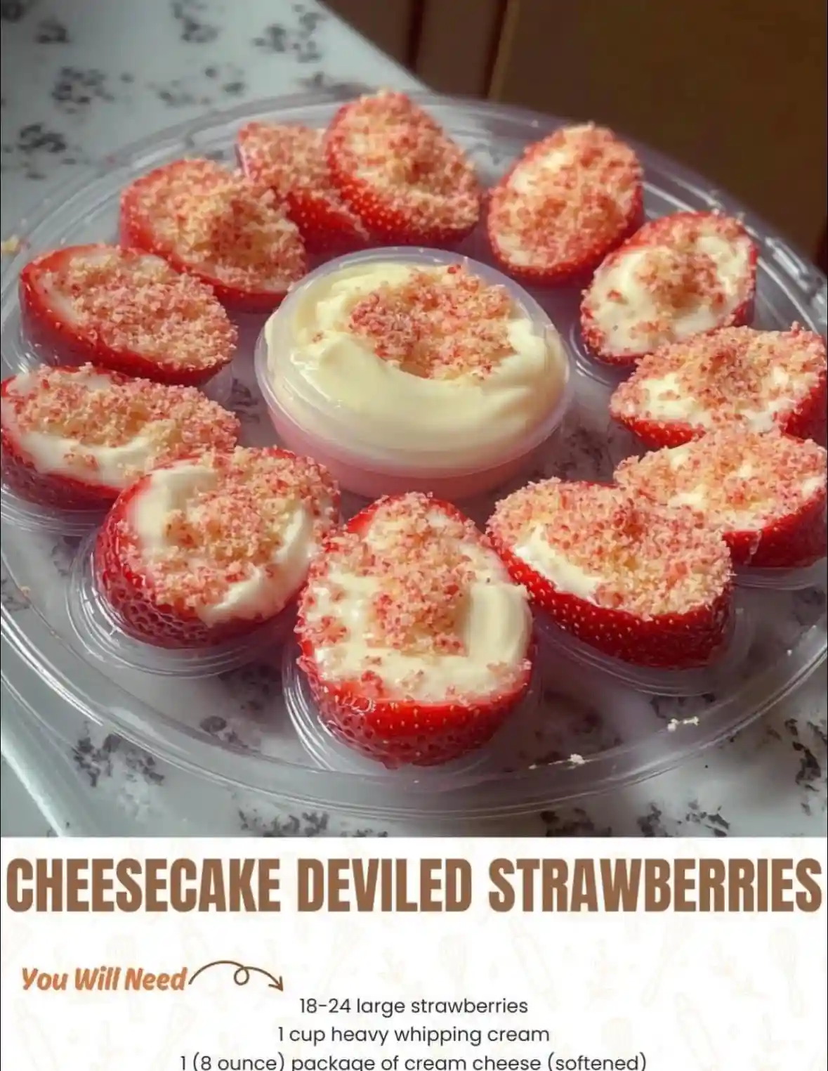 A clear plastic tray holds halved strawberries filled with white cream and topped with crushed red sugar, arranged around a…