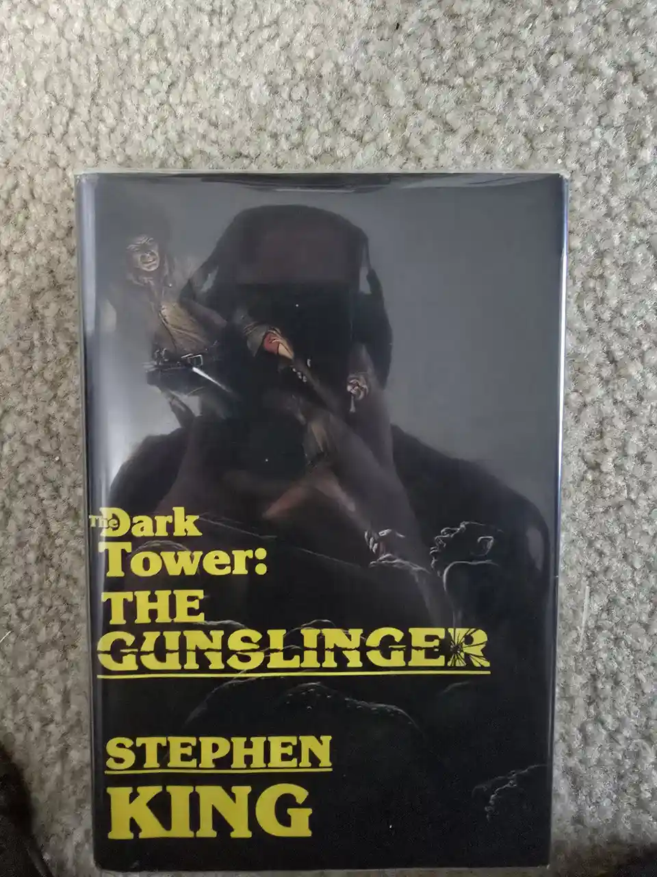 A physical copy of Stephen King's book 'The Dark Tower: The Gunslinger' is shown in its original black and yellow cover art…