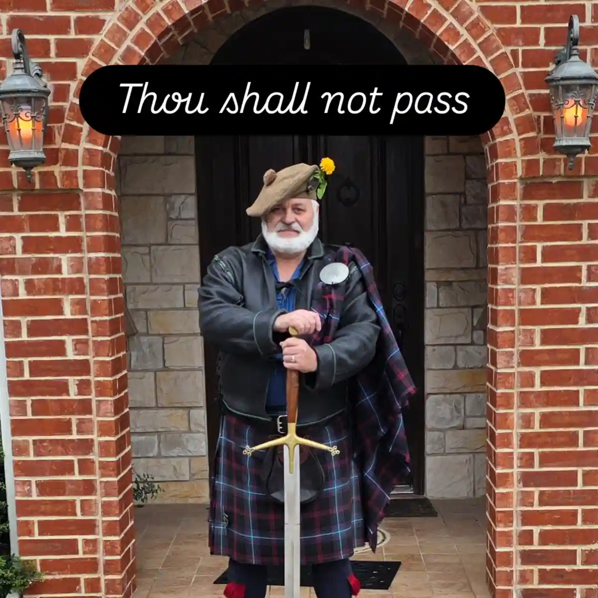 A man in a kilt and leather jacket stands in front of a brick archway holding a sword, with the text 'Thou shall not pass'…