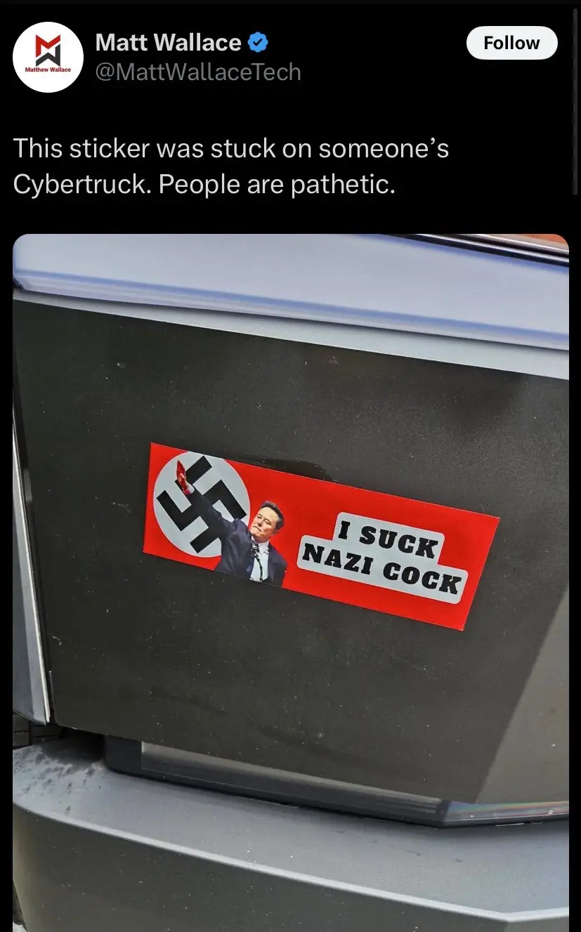 A red rectangular sticker is stuck on the black rear panel of a Tesla Cybertruck. The sticker features a swastika symbol on…