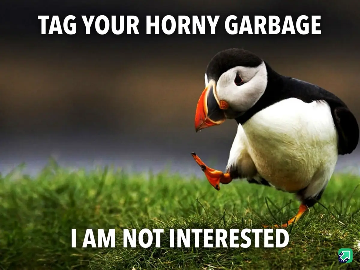 A puffin stands on green grass looking away with one foot lifted, overlaid with the text 'TAG YOUR HORNY GARbage' at the top…