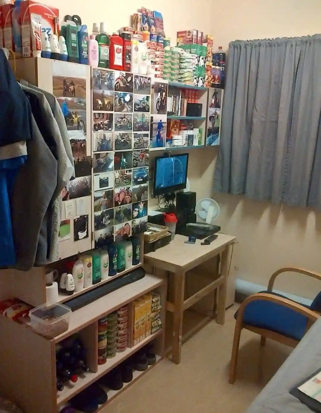 A cluttered bedroom with shelves overflowing with toiletries, snacks, and bottles, a wall covered in motorcycle photos, a…