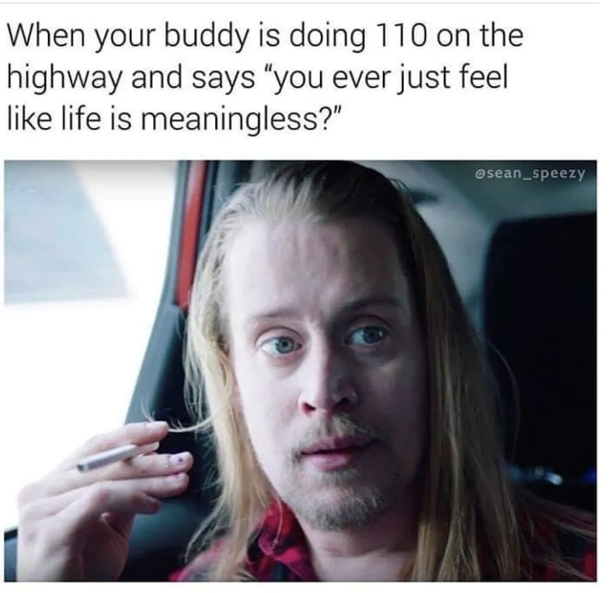 A man with long blonde hair and a goatee sits in a car, holding a cigarette, looking startled with wide eyes. The overlaid…