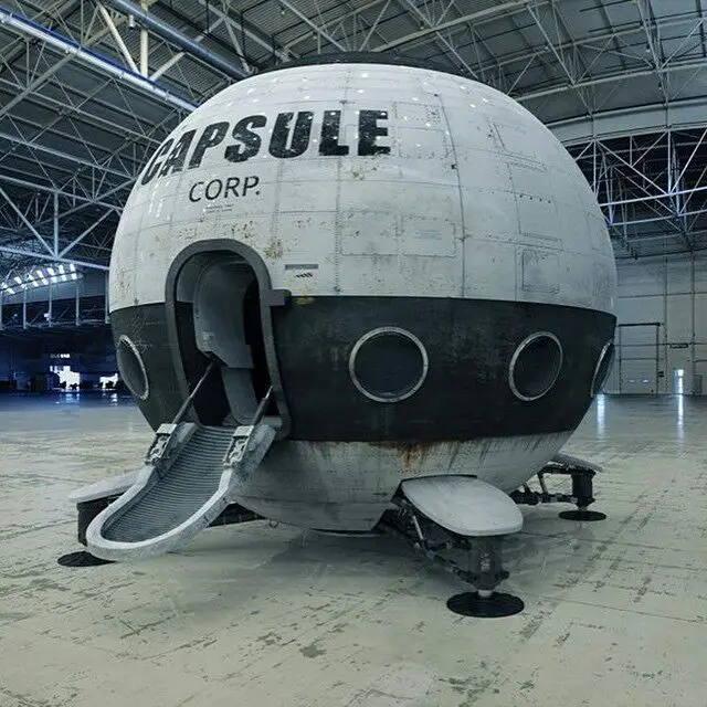 A large, spherical, retro-futuristic spaceship or capsule with 'CAPSULE CORP.' painted on its side sits inside a vast…
