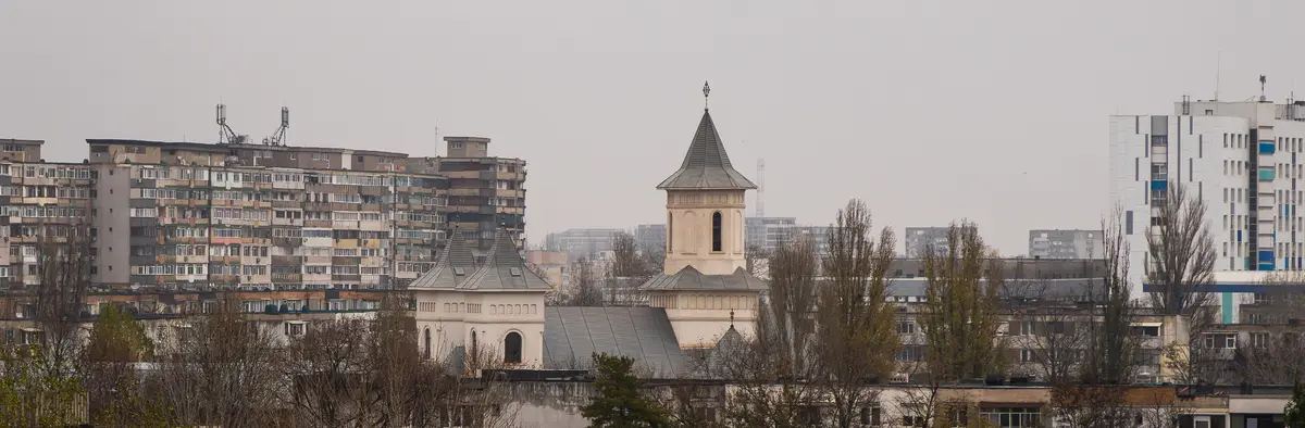 A vibrant new church shines amidst the rain-soaked Soviet-era skyline.