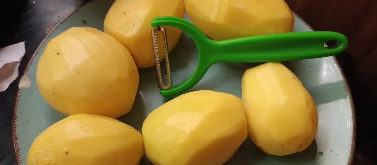 A close-up photo shows six peeled potatoes with a distinct faceted, geometric texture arranged on a light green ceramic…