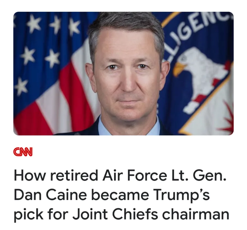 A formal headshot of a middle-aged man in military uniform, with an American flag and a Department of Defense Intelligence…