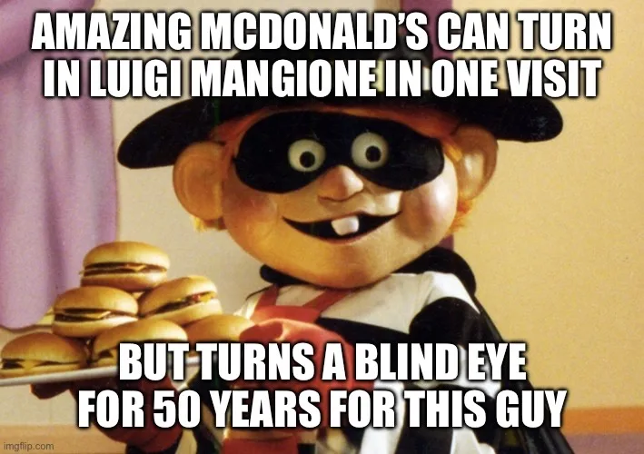 The image shows a puppet of the character 'The Masked Marvel' from McDonald's advertising, holding a tray of hamburgers. The…