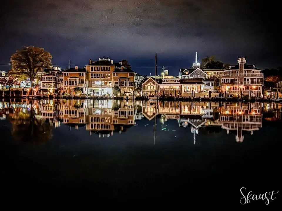 A nighttime photo of a waterfront town with brightly lit buildings reflecting in calm water, overlaid with the text 'i'm not…