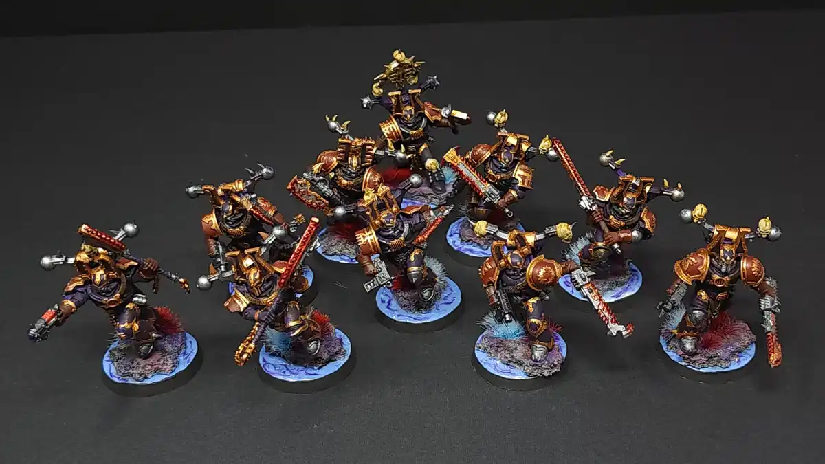 A collection of intricately painted miniature warhammer 40k space marines, all featuring identical purple and gold armor…