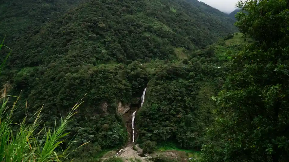A verdant mountain range rises majestically, its peaks shrouded in mist. A thunderous waterfall cascades down the rocky…