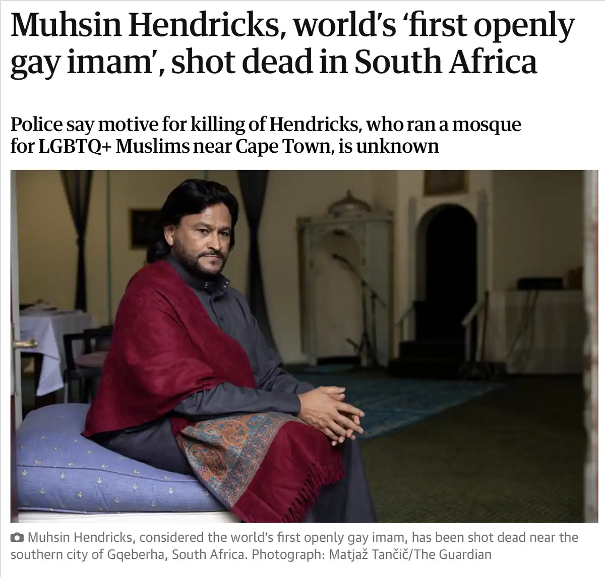 A news article screenshot shows a photo of Muhsin Hendricks, a man with dark hair and a beard, sitting on a blue cushion in…