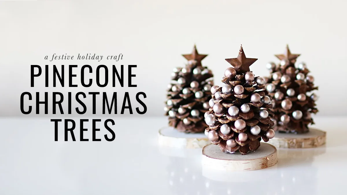 Three pinecones decorated with silver pearls and topped with metal stars sit on birch wood slices, presented as a holiday…