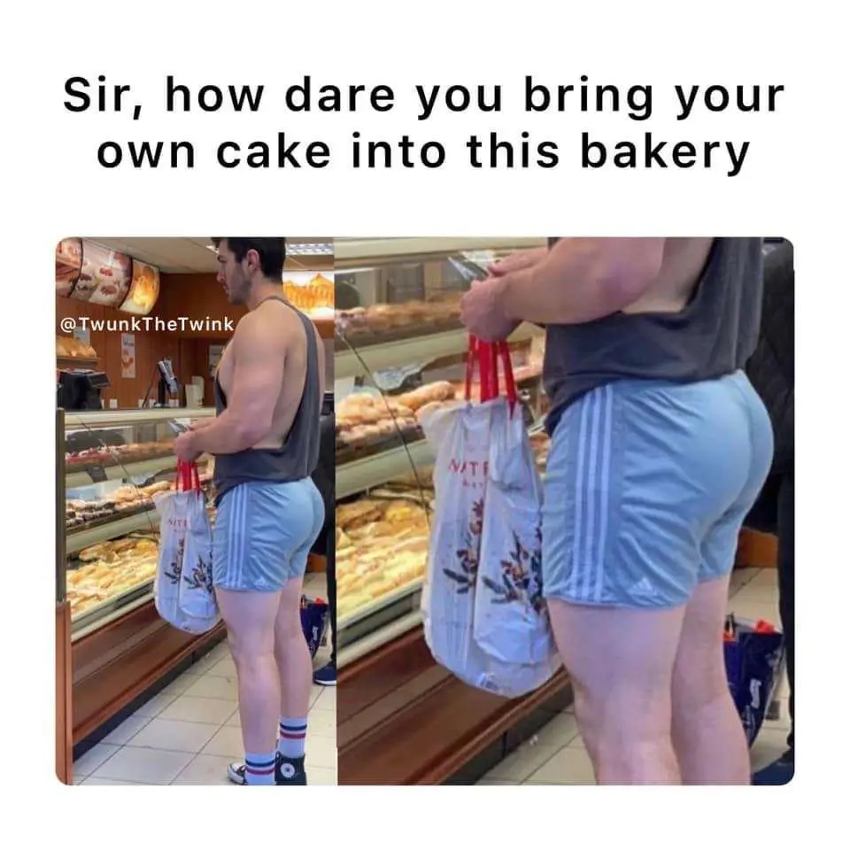 A man in a dark tank top and light blue athletic shorts stands in a bakery, holding two white shopping bags with red…