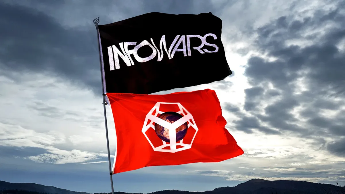 Two flags fly side-by-side against a cloudy sky: a black flag with 'INFOWARS' in white stylized text, and a red flag with a…