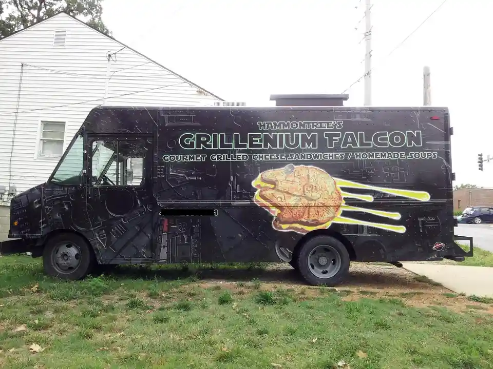A black food truck is parked on grass, decorated with a Star Wars theme. The side features the text 'HAMMONTREE'S…