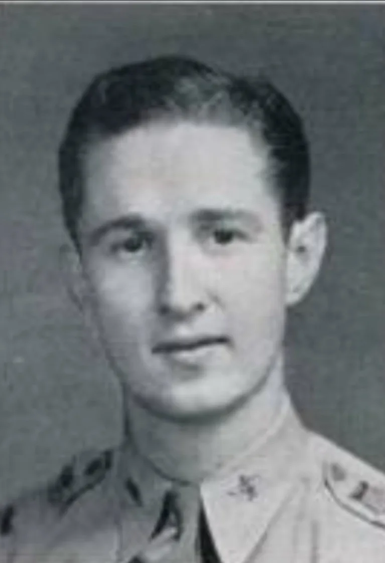 A black-and-white vintage portrait of a young man in a military uniform with insignia on his collar and shoulders, looking…