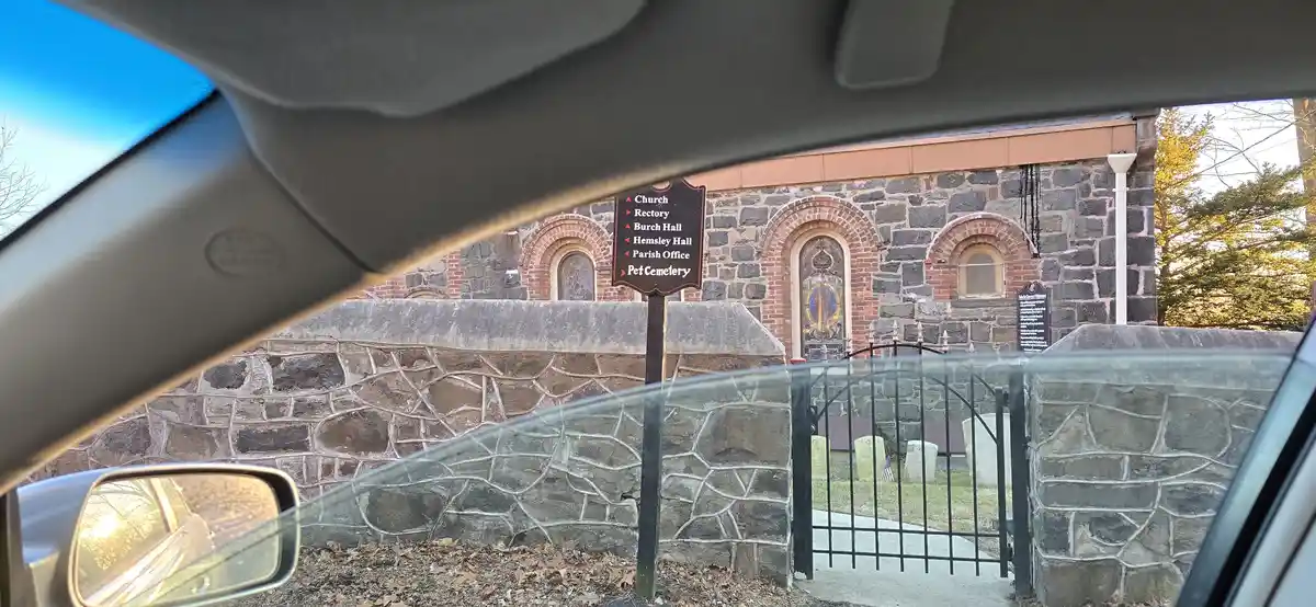 A photo taken from inside a car shows a directional sign listing locations including 'Pet Cemetery' at the bottom, next to a…